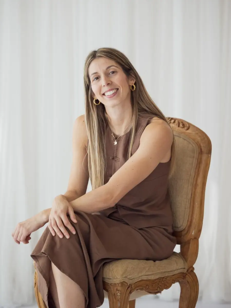 Ana González, psicóloga, sentada en una silla de madera con una sonrisa cercana