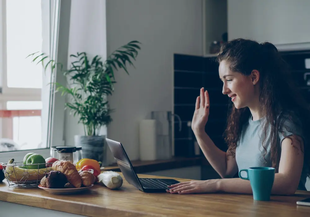 Terapia individual online: una persona saluda sonriente a través del ordenador desde su casa