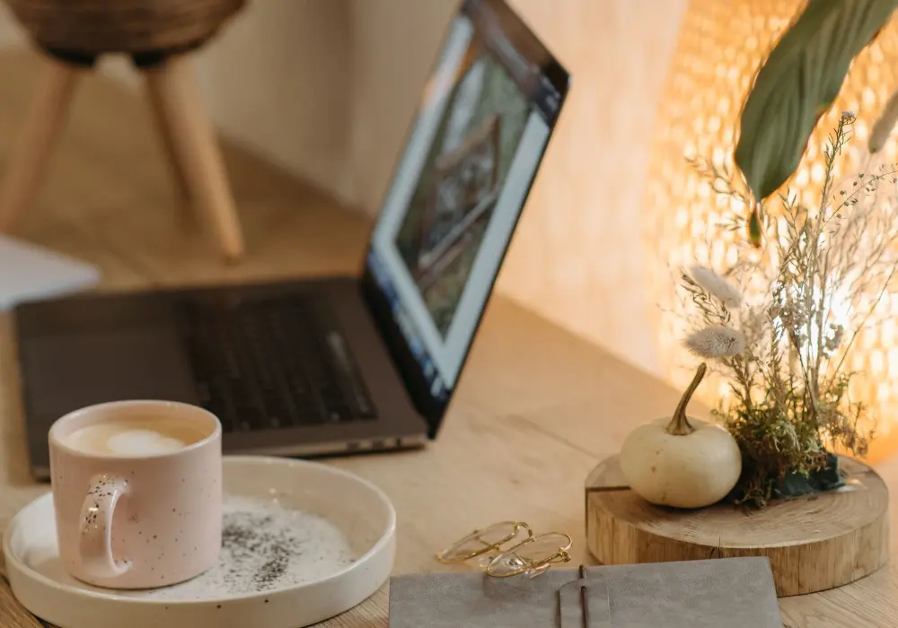Ordenador portátil abierto sobre una mesa de madera con flores secas y luz suave