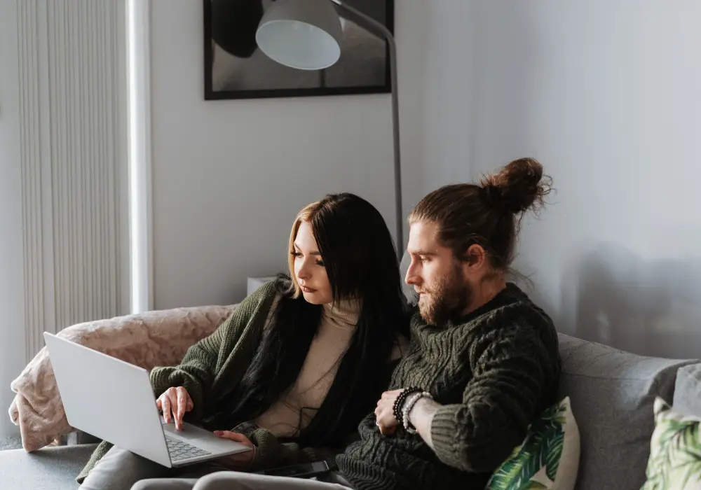 Terapia de pareja online: dos personas sentadas juntas en el sofá frente a un ordenador